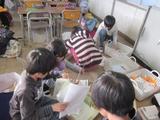 教室の床に座って作業する子ども達の写真