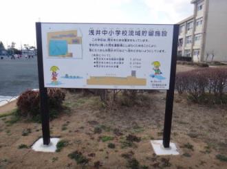 写真:浅井中小学校流域貯留施設の説明看板。この学校は、雨水をためる働きをもっています。学校内に降った雨を運動場にしばらくにためることにより、急にたくさんの雨水が川などへ流れ出さないようにしています。
