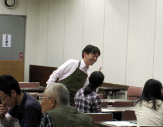 コミュニケーションのグループワークをしている参加者と笑顔で話す山田亮先生の写真