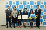 市長と表彰状を持った子ども、いちみんのぬいぐるみを持った子ども、認定証を持った子ども、市長、教諭2人(貴船小)