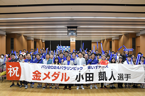 横断幕を前に記念撮影している様子の写真