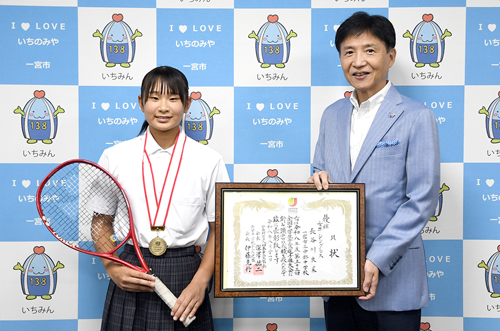 来訪者がラケットを、市長が賞状を持って記念撮影した写真