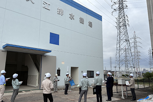 市長と関係者が大江排水機場の前で説明を聞いている様子の写真