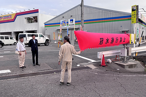 エアー遮断機の前で、市長と関係者が説明を受けている様子の写真
